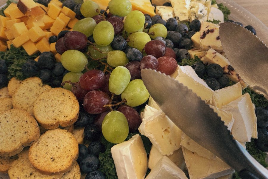 Cheese tray with brie, cheddar and blue cheese, grapes, blueberries and crackers